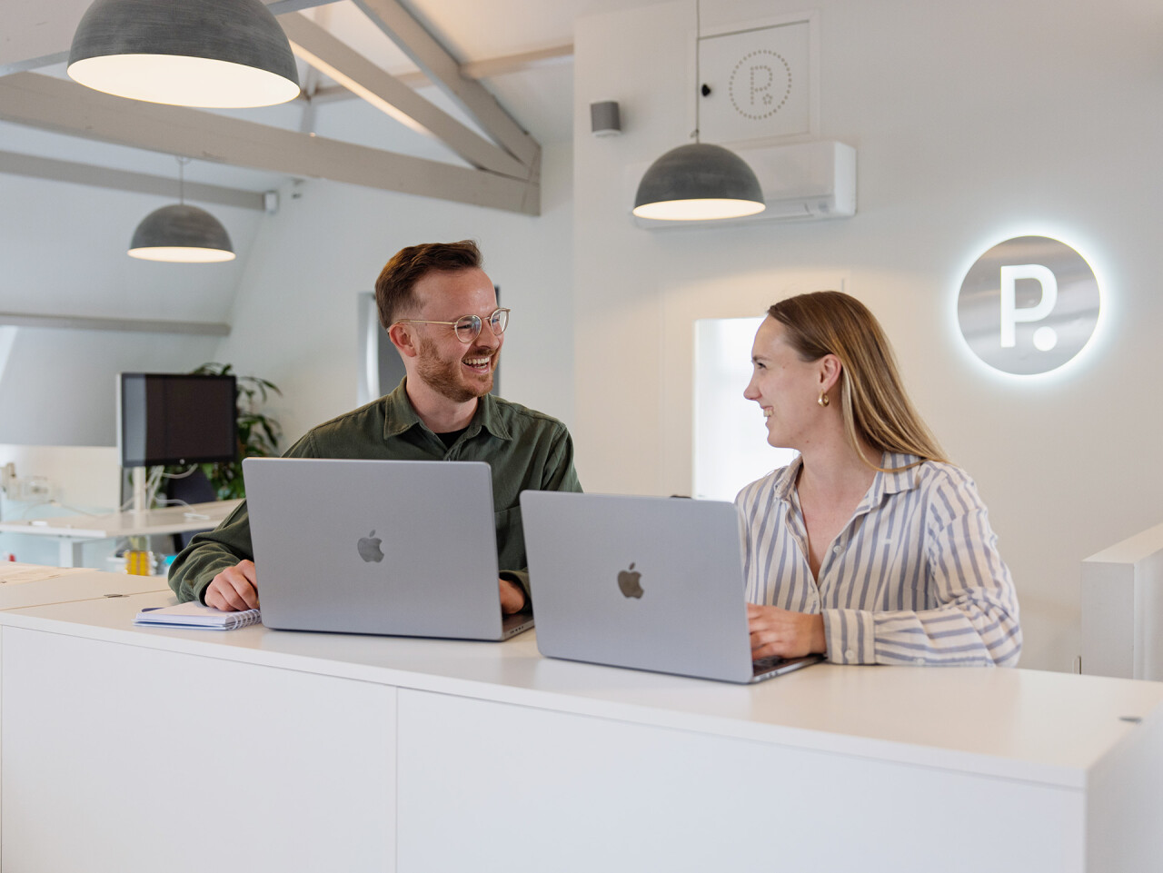 Koen en Lois lachen aan tafel met laptops